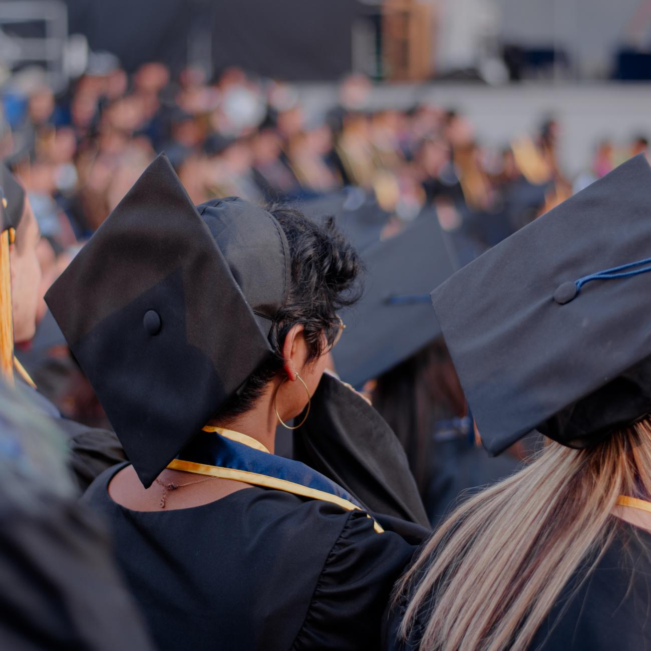 A backshot of two students wearing a cap and gown at the CDSS commencement.