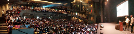 Panoramic shot of lecturer in Zellerbach hall for Data 8 with many students filling out seats